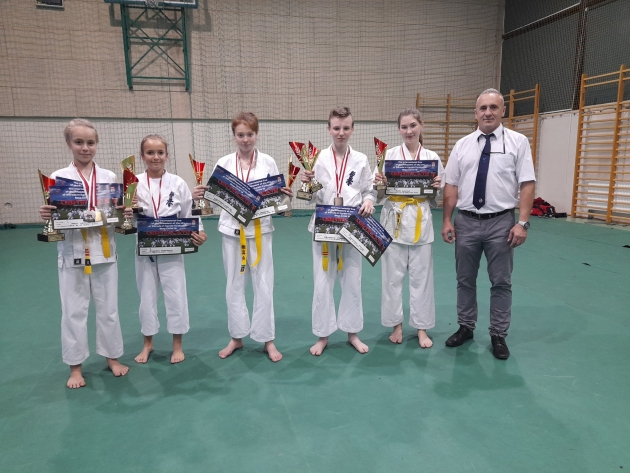 Na zdjęciu sensei Paweł Olszewski oraz zawodnicy LKKK z dyplomami, medlami i pucharami.